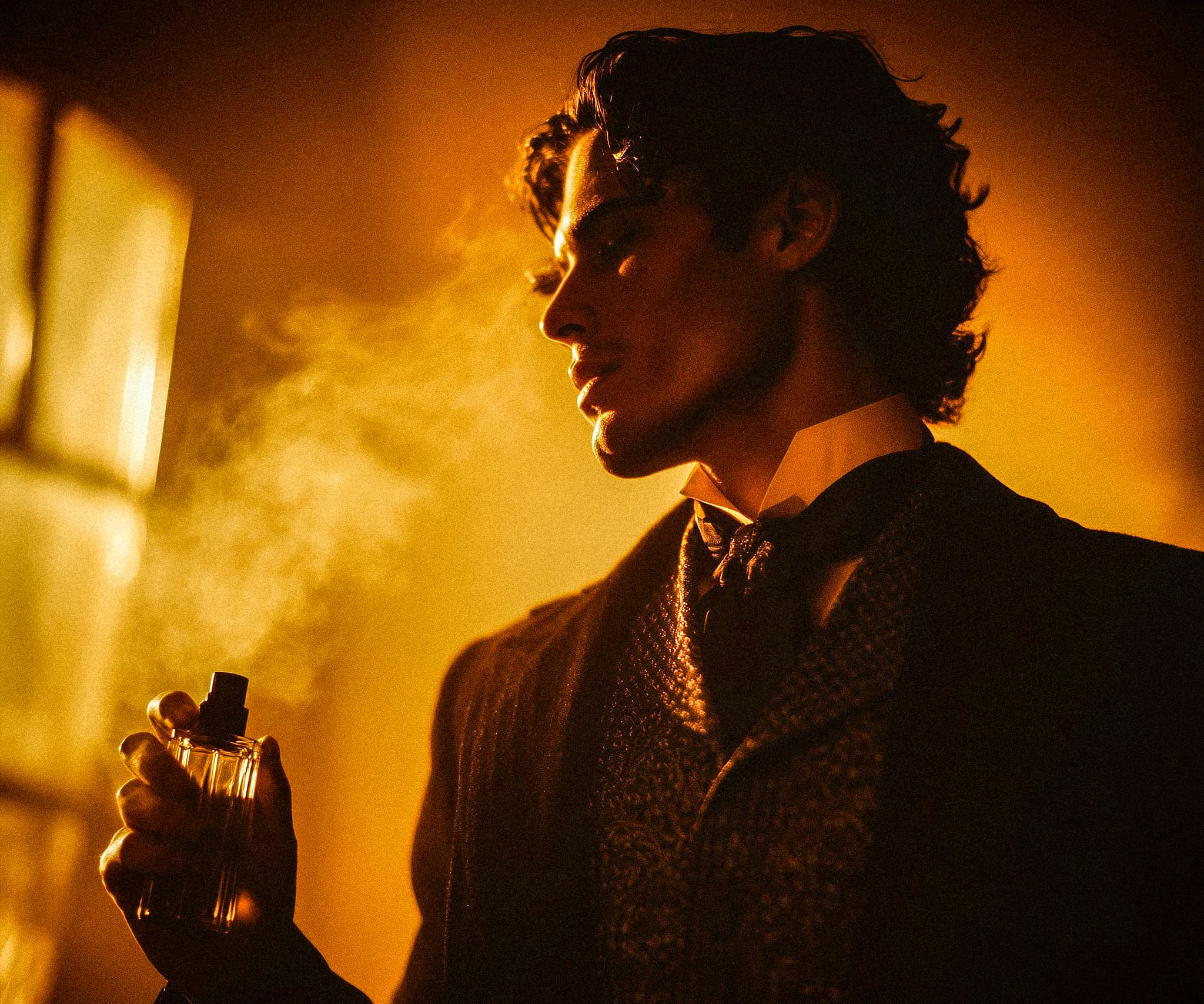 Victorian-style man spraying perfume in warm light, symbolising the luxurious and historic use of tobacco in perfumery